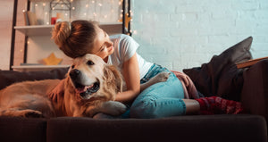 Girl hugging golden retriever dog on couch